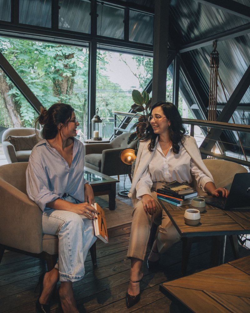 Two colleagues talking in a bright timber-and-glass coworking lounge